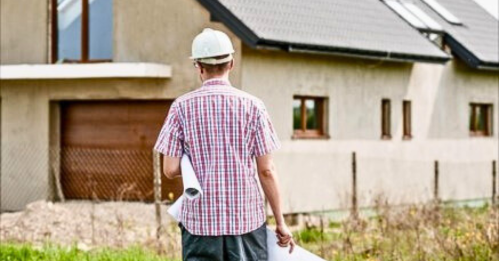 Contractor approaching a house with a hard hat and house plans