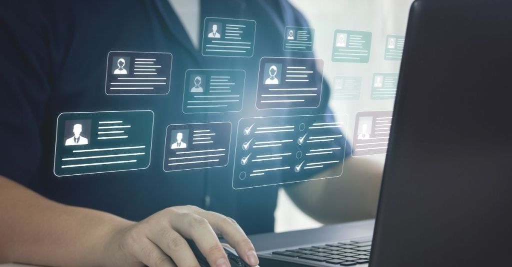 A man working on a laptop with a 3-D display of profile icons hovering above the keyboard.