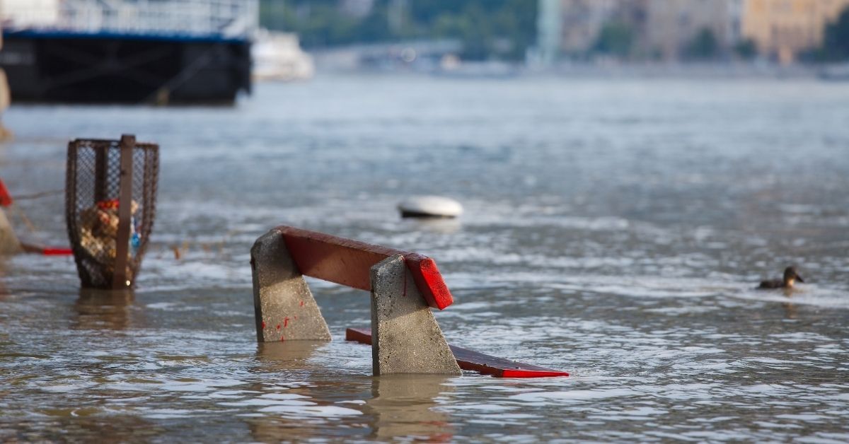 A street bench in a flooded road.
