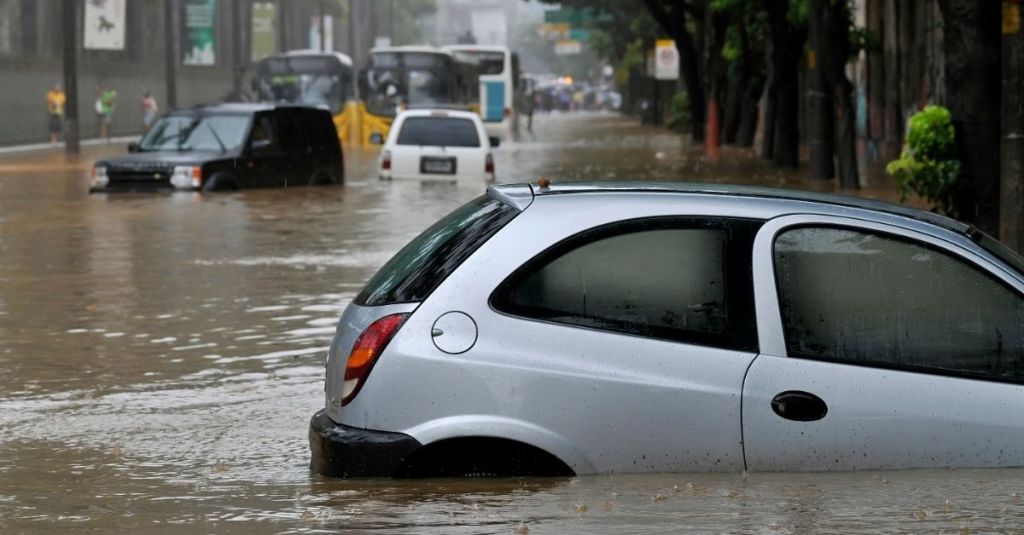 Cars and buses scattered along a street during a flash flood.