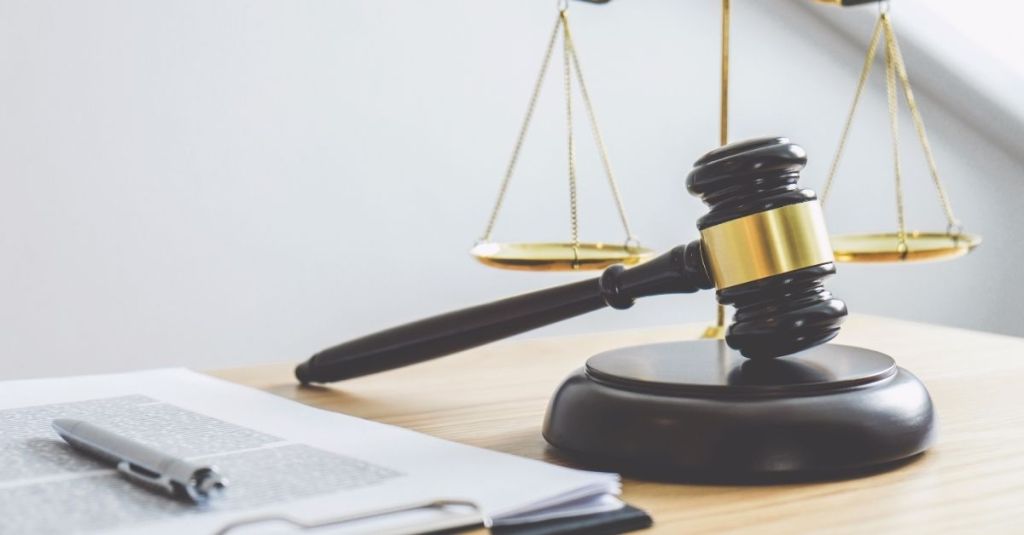 A gavel and scale of justice stand beside a clipboard.