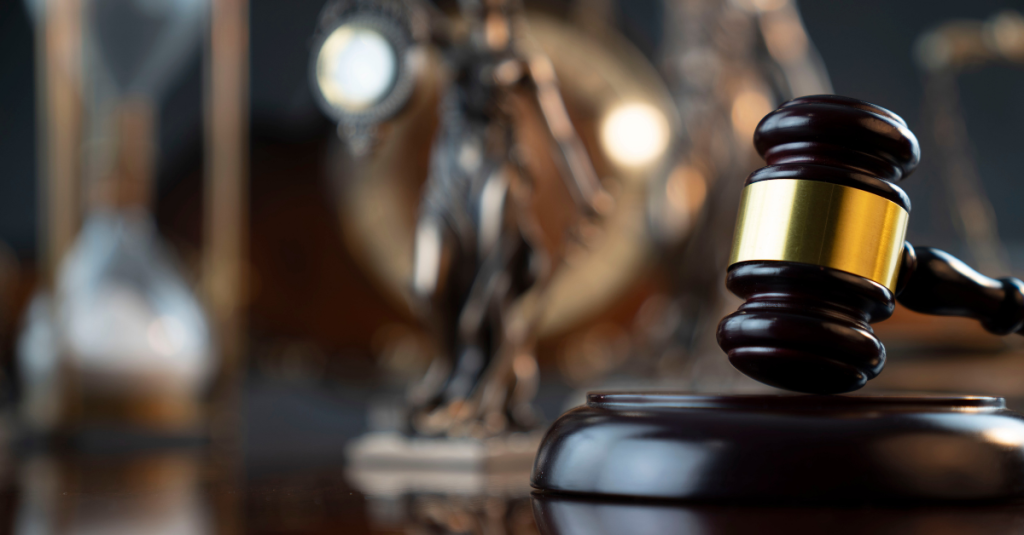Gavel on pedestal with lady justice desk statute in the background