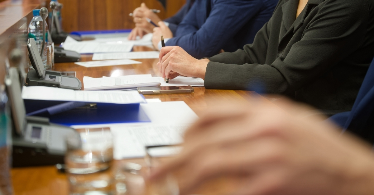 Low view of a row of people sitting in a chamber meeting.