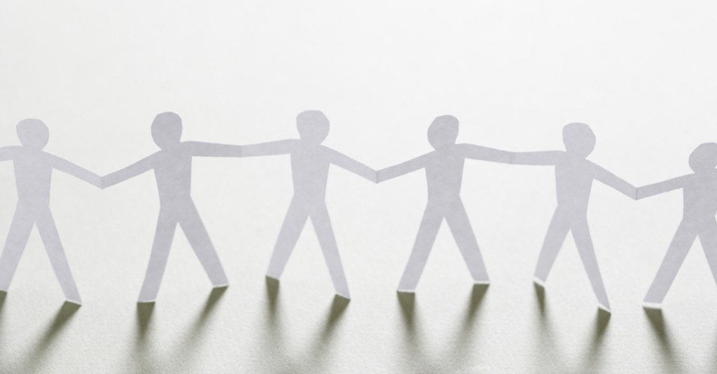 A string of paper human body cut-outs connected to one another.