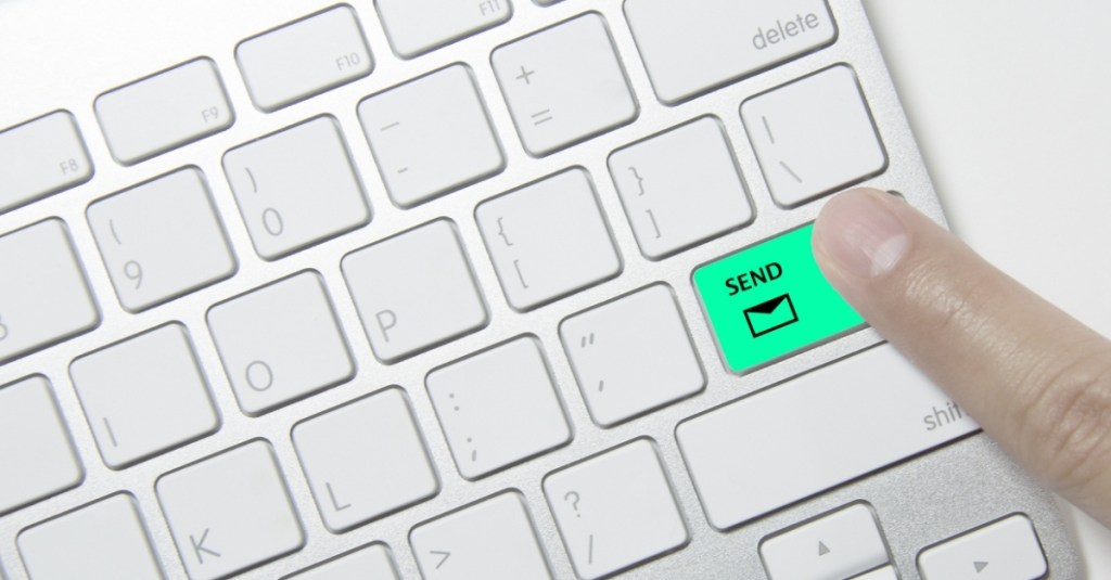 A finger pressing the send button on a computer keyboard.