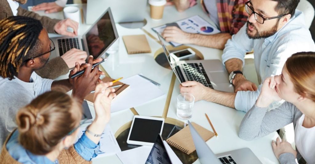 Team members speaking to one another at a table.