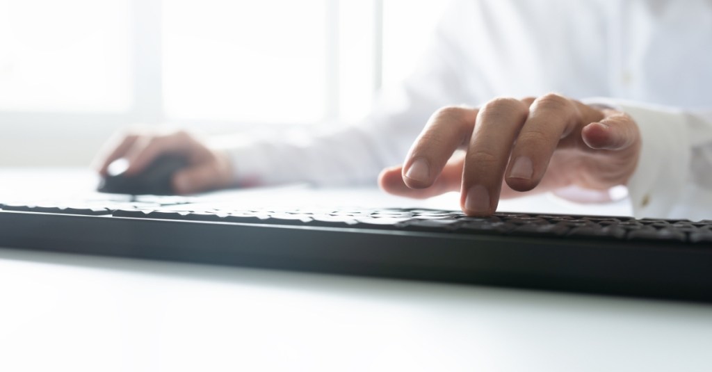 Worm's eye view of a person typing on a computer keyboard.