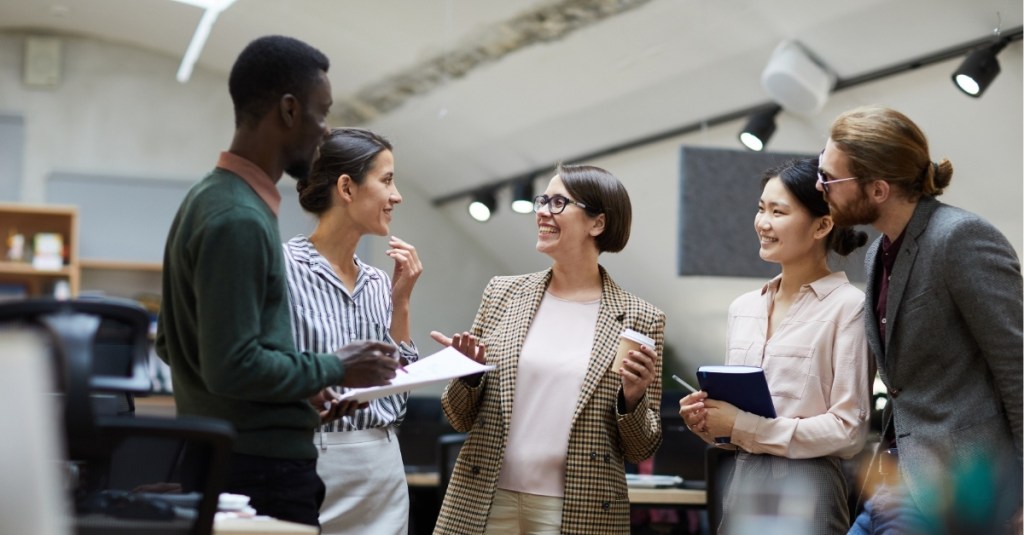 A group of business people cheerfully laughing and smiling in an office.