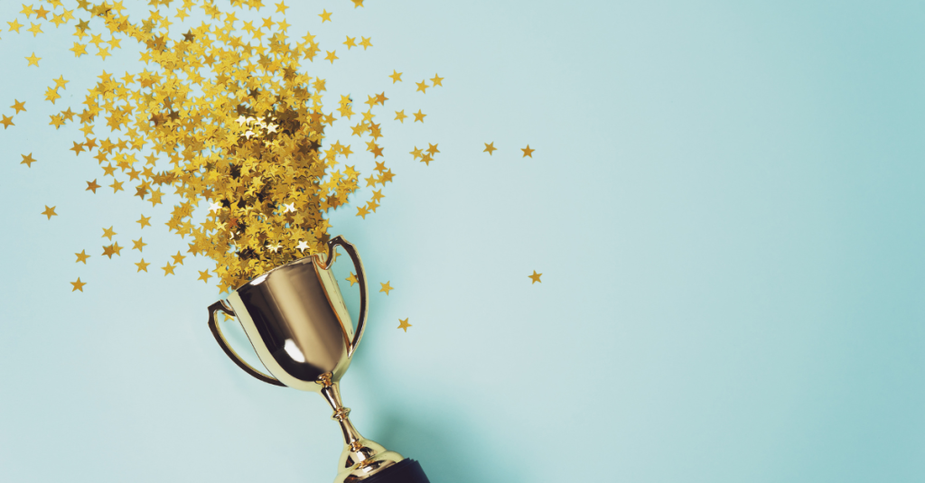 Trophy laid on a blue background with star confetti spilling out of the cup