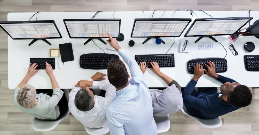A team leader pointing at a worker's computer screen.