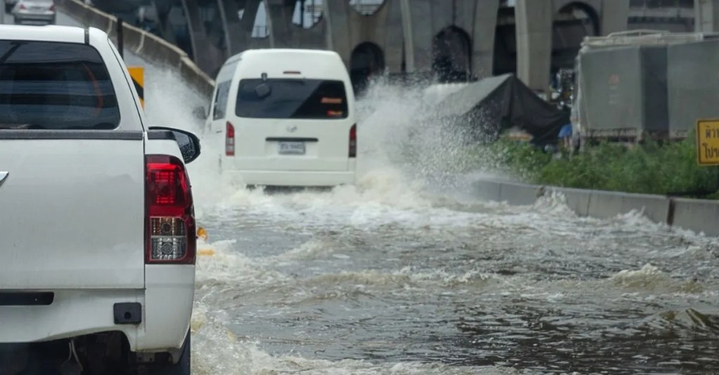 Cars driving through a flooded road.