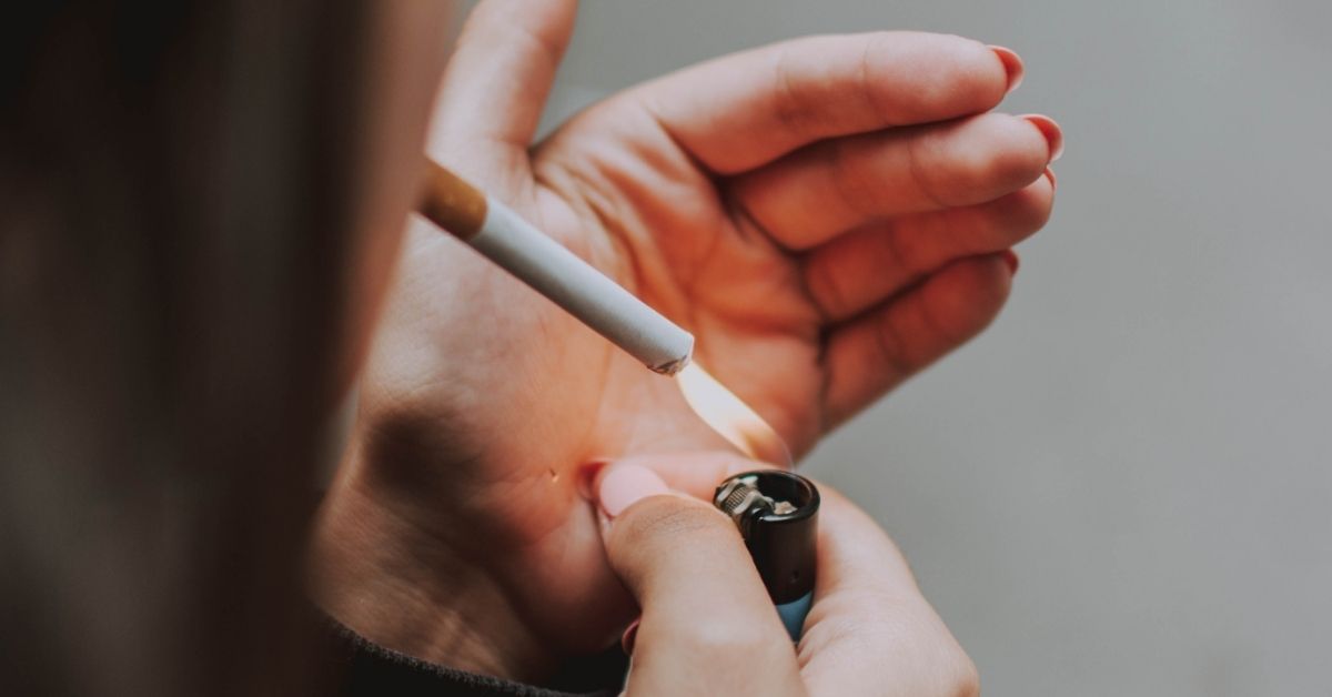 A woman lighting a cigarette with a lighter.