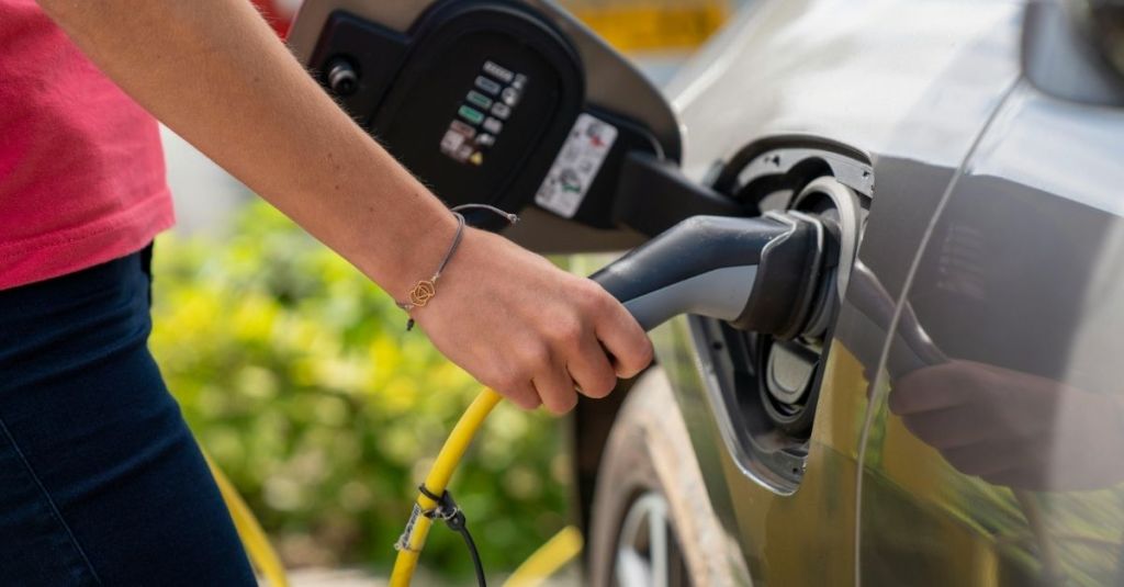 A woman plugging her car into an electric vehicle charging station.